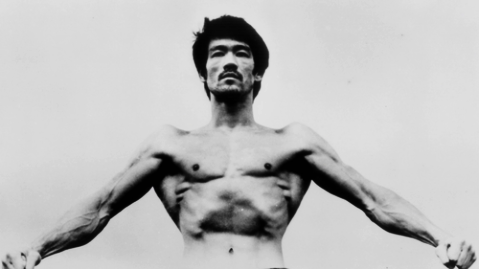 Photo of Bruce Lee flexing his lats